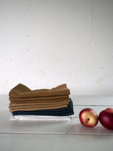 different washed linen napkins on a table with two apples