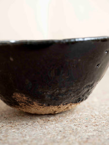 close-up of handmade ceramic with a rough clay and shiny black glaze