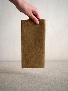 woman holding a natural washed linen folded napkin from Linge Particulier
