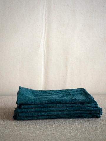 pile of dark green linen napkins with a waffle structure by Linge Particulier