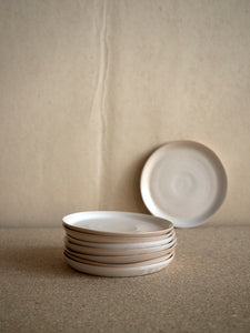 pile of small handmade ceramic plats with a matt white glaze at M AAH